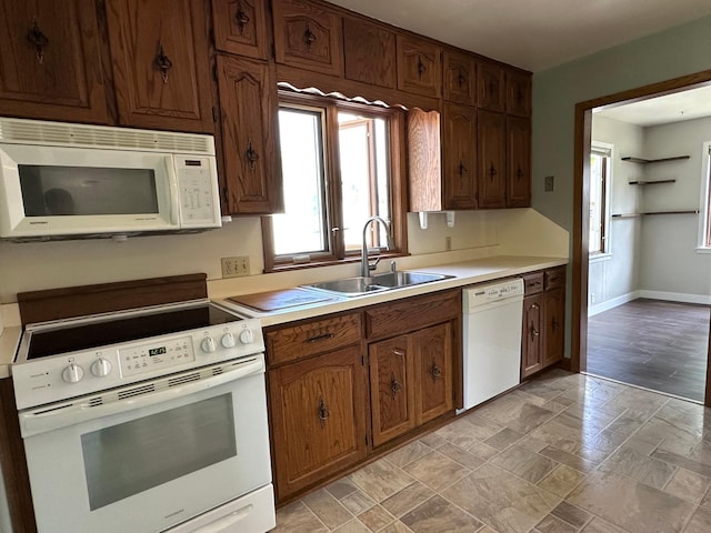 kitchen with white appliances, a sink, plenty of natural light, and light countertops