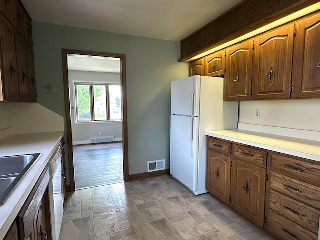 kitchen with white appliances, light countertops, baseboards, stone finish floors, and a sink