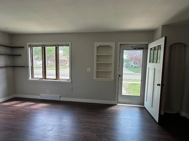 foyer featuring plenty of natural light, baseboards, and dark wood finished floors
