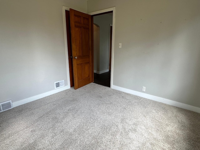 carpeted spare room with arched walkways and baseboards