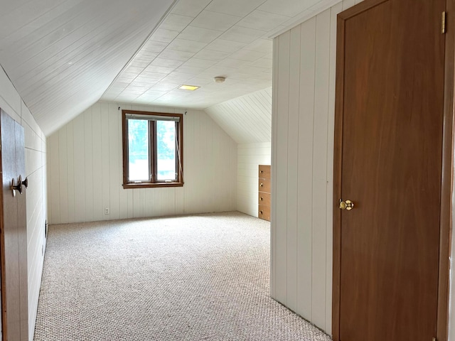 bonus room featuring carpet, vaulted ceiling, and wood walls