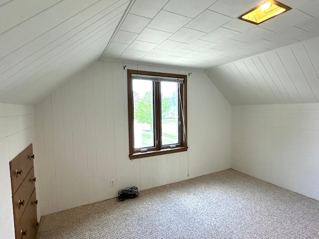bonus room with carpet, lofted ceiling, and wooden walls
