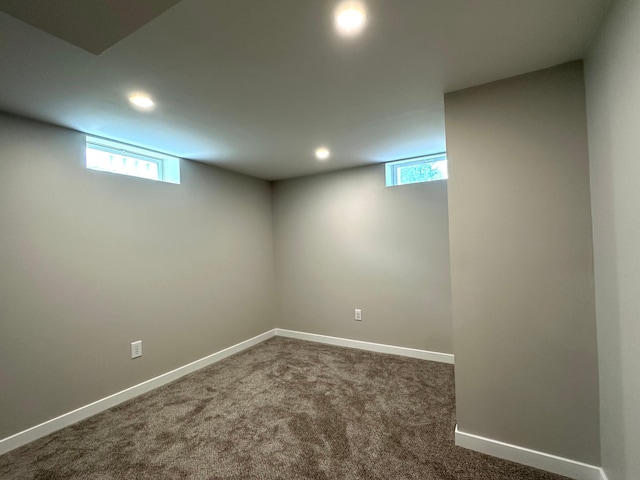 below grade area featuring recessed lighting, healthy amount of natural light, dark colored carpet, and baseboards