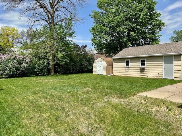 view of green lawn featuring a storage shed and an outbuilding