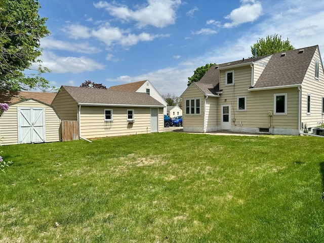 back of property featuring a shed, a lawn, an outbuilding, and roof with shingles