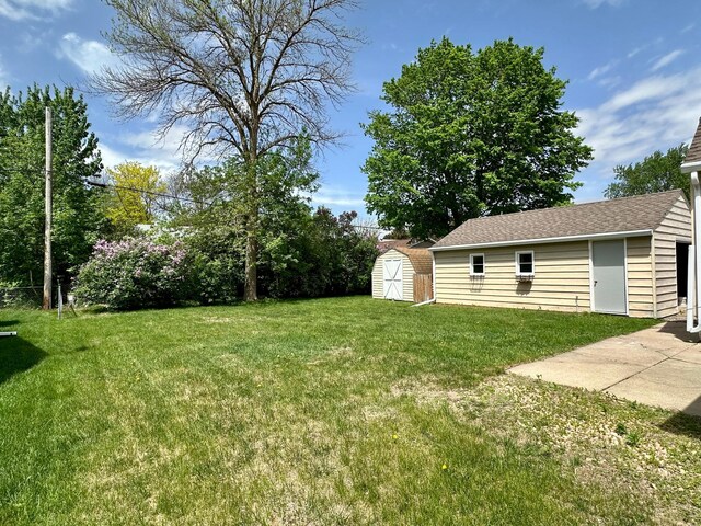 view of grassy yard with an outbuilding and a storage shed