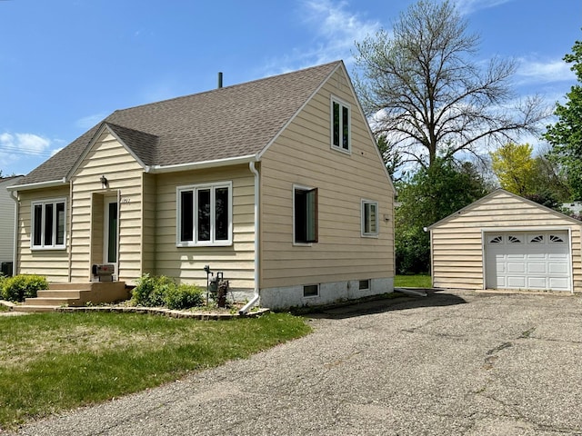 bungalow-style house featuring an outdoor structure, a garage, roof with shingles, and driveway