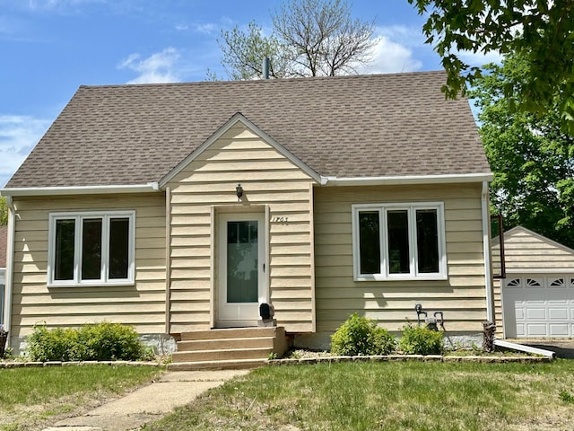 view of front of house featuring roof with shingles, entry steps, a detached garage, and an outbuilding