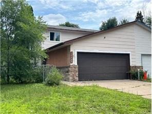 10989 Osage St NW, Coon Rapids, MN 55433 - view of front facade featuring stone siding, a front yard, and an attached garage