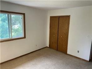 10989 Osage St NW, Coon Rapids, MN 55433 - unfurnished bedroom with multiple windows, a closet, and baseboards
