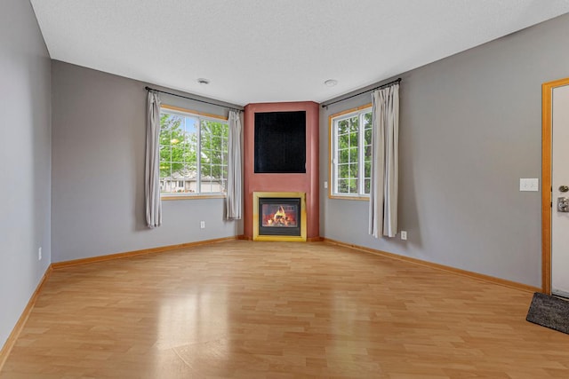 13037 Europa Trail Way N Unit A, Hugo, MN 55038 - unfurnished living room with light wood-type flooring, plenty of natural light, and a glass covered fireplace