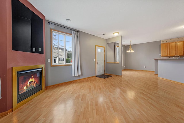 13037 Europa Trail Way N Unit A, Hugo, MN 55038 - unfurnished living room featuring light wood finished floors, a glass covered fireplace, and baseboards
