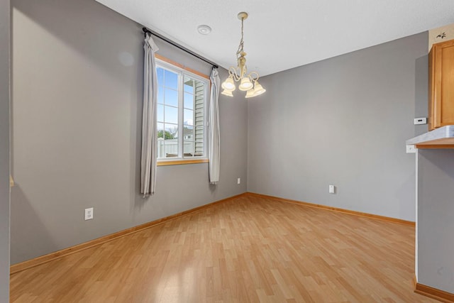 13037 Europa Trail Way N Unit A, Hugo, MN 55038 - unfurnished room featuring light wood finished floors, baseboards, and a chandelier