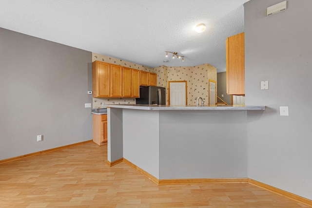 13037 Europa Trail Way N Unit A, Hugo, MN 55038 - kitchen with freestanding refrigerator, baseboards, light wood finished floors, a textured ceiling, and a peninsula