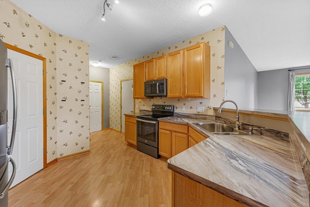 13037 Europa Trail Way N Unit A, Hugo, MN 55038 - kitchen featuring stainless steel appliances, wallpapered walls, light wood finished floors, a sink, and a peninsula