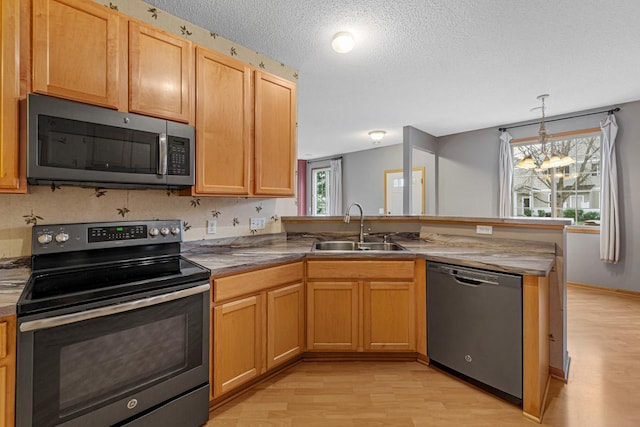 13037 Europa Trail Way N Unit A, Hugo, MN 55038 - kitchen featuring appliances with stainless steel finishes, a sink, a peninsula, light wood-style flooring, and a textured ceiling