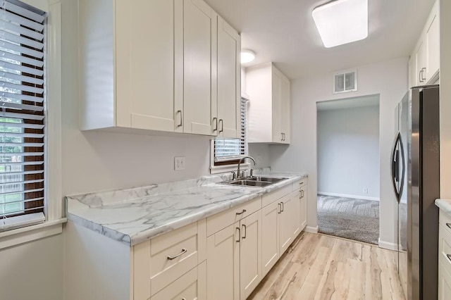 11131 Magnolia St NW, Coon Rapids, MN 55448 - kitchen featuring a sink, freestanding refrigerator, light wood-type flooring, light countertops, and white cabinets