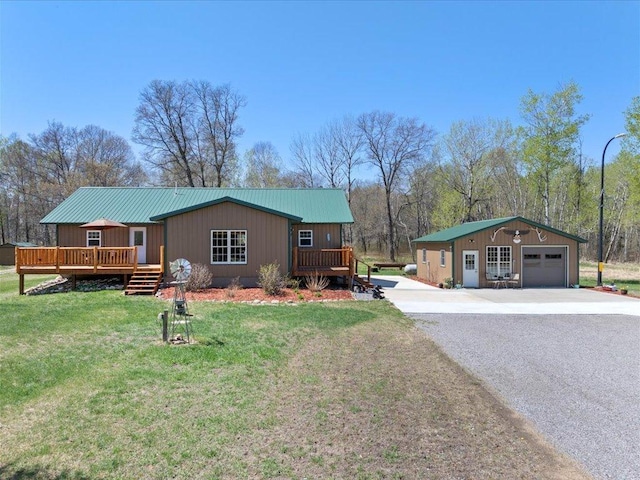 1465 State 84 NW, Backus, MN 56435 - view of front of house featuring a wooden deck, concrete driveway, a front lawn, a garage, and an outbuilding