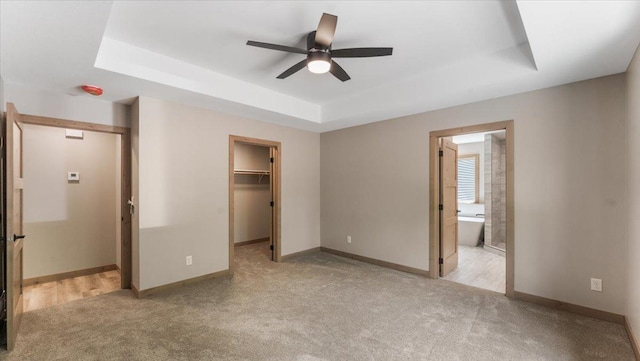 2948 N Oaks Ln NW, Garfield, MN 56332 - unfurnished bedroom with a tray ceiling, carpet flooring, a spacious closet, and baseboards