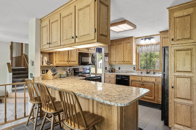 11946 180th St, Milaca Twp, MN 56353 - kitchen featuring black appliances, a textured ceiling, a sink, a peninsula, and a kitchen breakfast bar