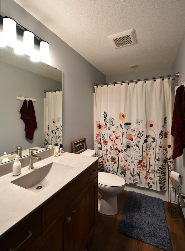1800 20th Avenue Cir NE, Kasson, MN 55944 - full bathroom with wood finished floors, vanity, toilet, a textured ceiling, and a shower with shower curtain