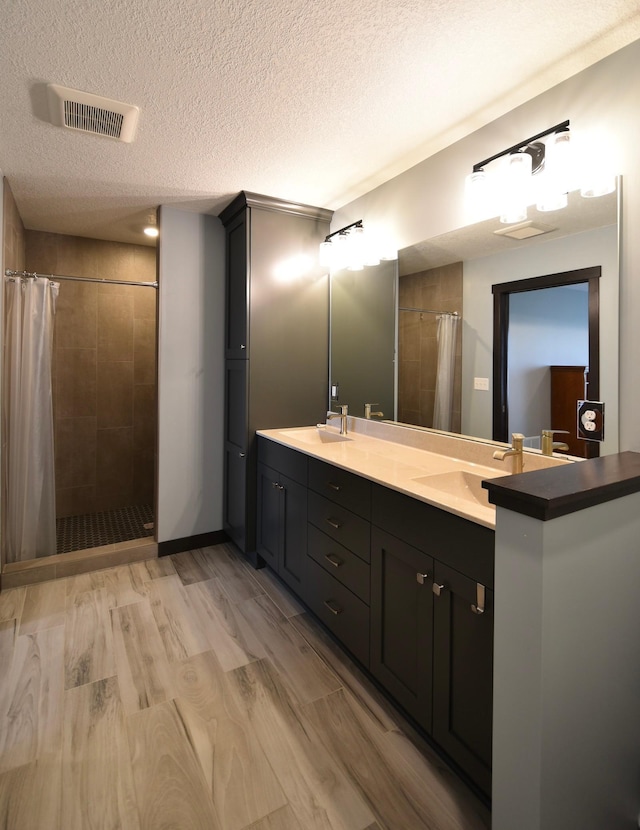 1800 20th Avenue Cir NE, Kasson, MN 55944 - bathroom featuring a textured ceiling, a tile shower, double vanity, and wood finished floors