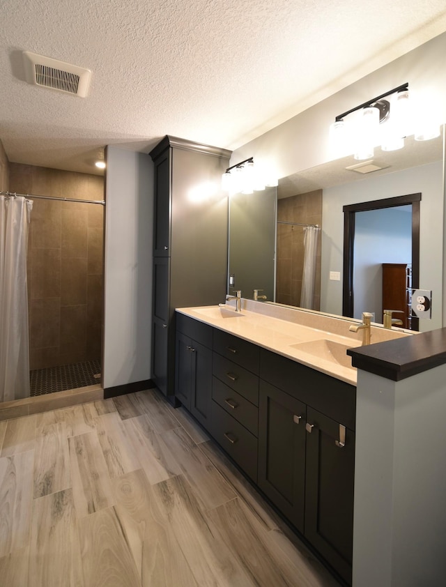 1800 20th Avenue Cir NE, Kasson, MN 55944 - bathroom featuring a tile shower, double vanity, a textured ceiling, and wood finished floors