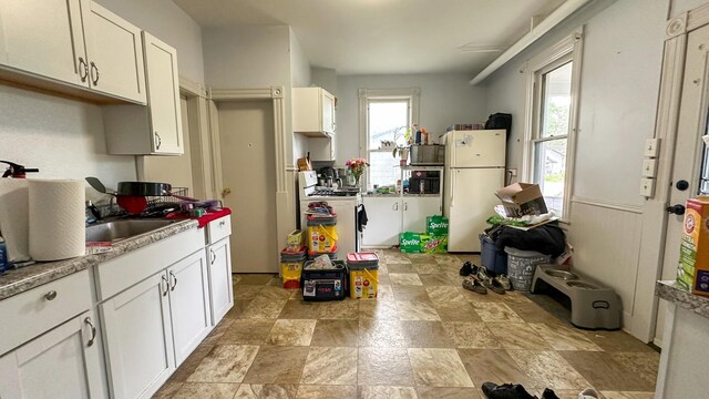 226 3rd Ave NE, Saint Cloud, MN 56304 - kitchen with white appliances, a sink, light stone finish floors, and white cabinets