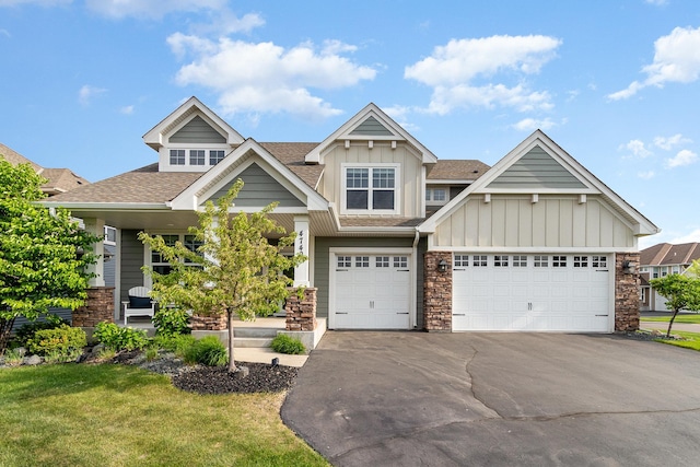 4740 Ashton Curv, Woodbury, MN 55129 - view of front of house featuring board and batten siding, asphalt driveway, roof with shingles, stone siding, and a front yard