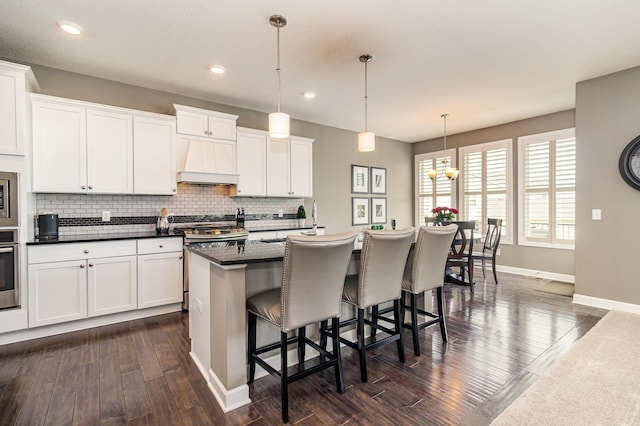 4740 Ashton Curv, Woodbury, MN 55129 - kitchen with custom range hood, baseboards, dark wood-style floors, decorative backsplash, and dark countertops