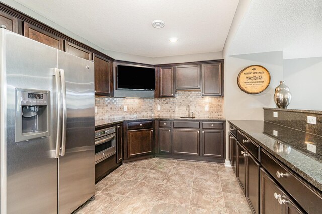 4740 Ashton Curv, Woodbury, MN 55129 - kitchen with appliances with stainless steel finishes, dark brown cabinetry, dark stone counters, a sink, and tasteful backsplash