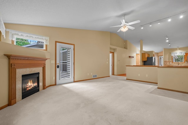 13403 96th Pl N, Maple Grove, MN 55369 - unfurnished living room featuring lofted ceiling, a ceiling fan, a tile fireplace, track lighting, and healthy amount of natural light