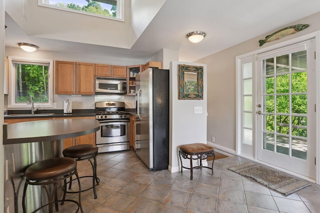 3806 Sunset Dr, Spring Park, MN 55384 - kitchen with stainless steel appliances, a sink, dark countertops, brown cabinets, and a breakfast bar
