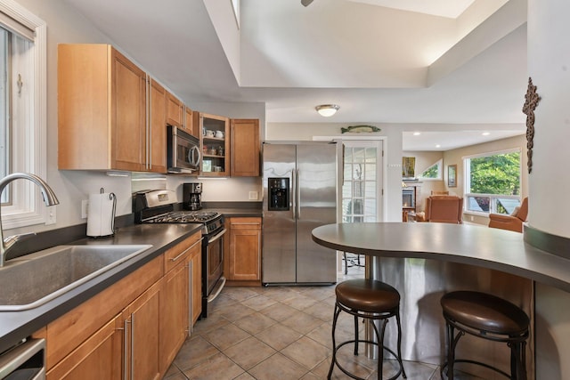 3806 Sunset Dr, Spring Park, MN 55384 - kitchen featuring appliances with stainless steel finishes, a sink, a kitchen breakfast bar, dark countertops, and brown cabinetry