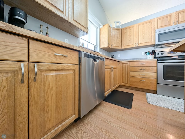 kitchen featuring stainless steel appliances, light brown cabinets, light wood-type flooring, light countertops, and lofted ceiling