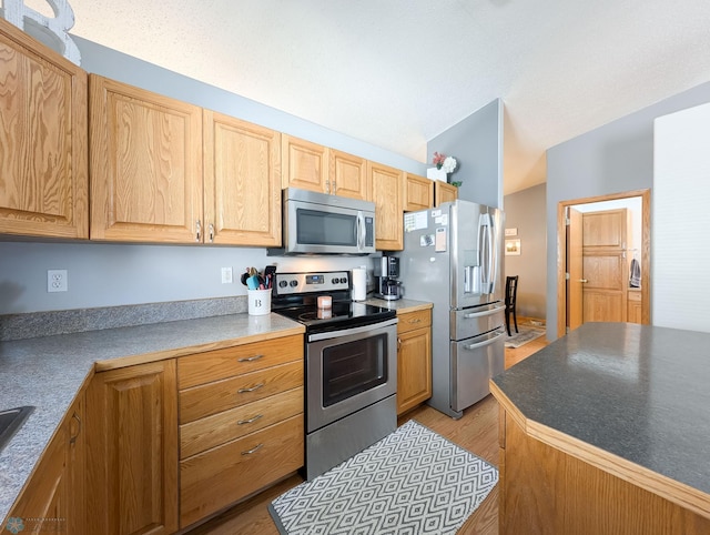 kitchen featuring stainless steel appliances, light wood-style floors, and light brown cabinets
