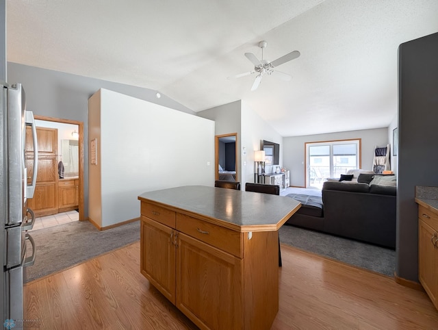 kitchen featuring light wood-style flooring, freestanding refrigerator, lofted ceiling, ceiling fan, and open floor plan