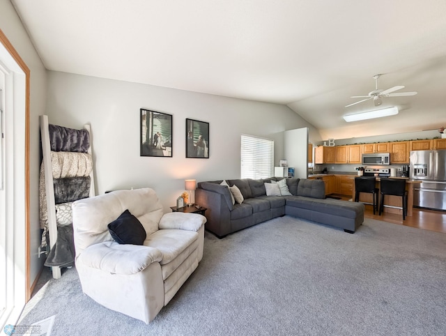 living area with light colored carpet, vaulted ceiling, and a ceiling fan