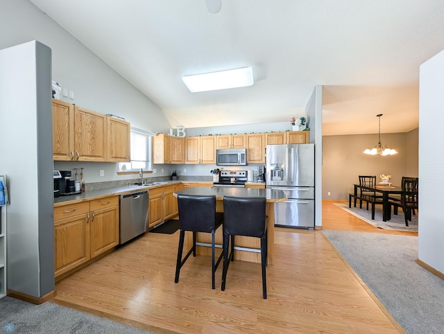 kitchen with stainless steel appliances, vaulted ceiling, a sink, a chandelier, and light wood-type flooring