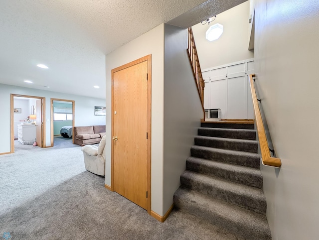 staircase with carpet flooring, recessed lighting, baseboards, and a textured ceiling