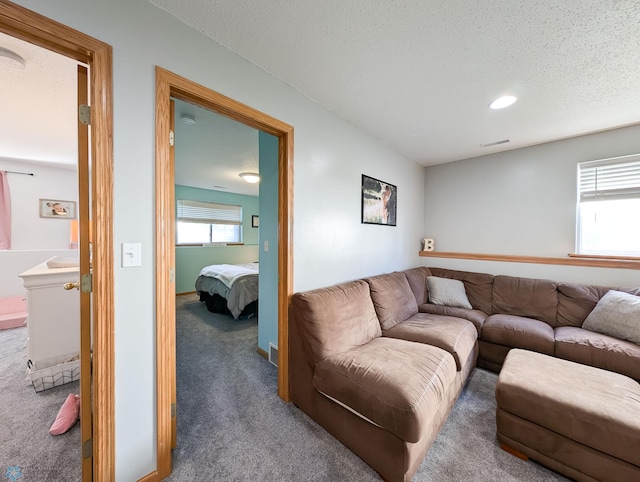carpeted living area with a textured ceiling and recessed lighting