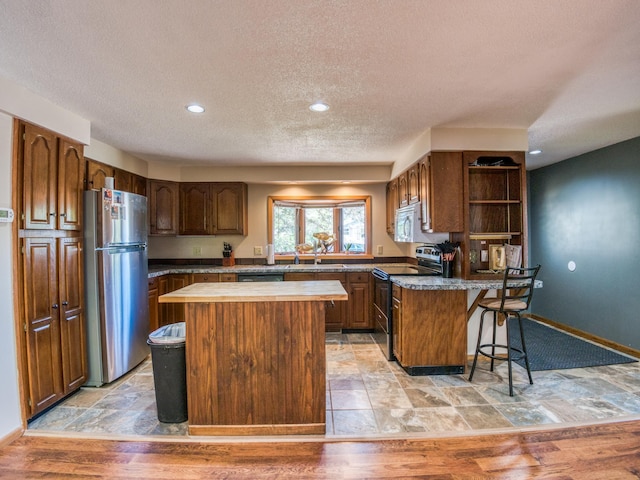 300 27th St NE, Bemidji, MN 56601 - kitchen with appliances with stainless steel finishes, a kitchen breakfast bar, open shelves, a sink, and a textured ceiling