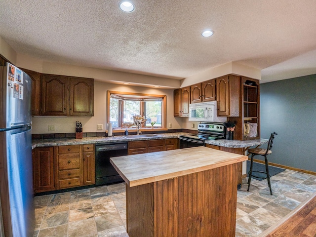 300 27th St NE, Bemidji, MN 56601 - kitchen with appliances with stainless steel finishes, wood counters, a textured ceiling, a sink, and a kitchen island