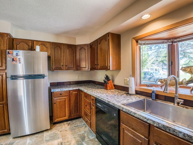 300 27th St NE, Bemidji, MN 56601 - kitchen featuring freestanding refrigerator, black dishwasher, a sink, brown cabinetry, and a textured ceiling
