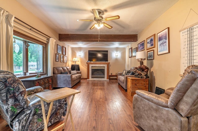 504 Laurel St, Fergus Falls, MN 56537 - living area with a glass covered fireplace, beam ceiling, wood finished floors, a ceiling fan, and a textured ceiling