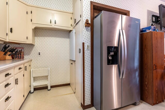 504 Laurel St, Fergus Falls, MN 56537 - kitchen with stainless steel fridge with ice dispenser, cream cabinets, light countertops, and wallpapered walls