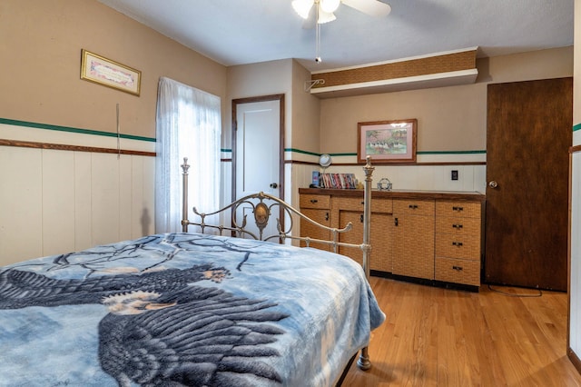 504 Laurel St, Fergus Falls, MN 56537 - bedroom with light wood finished floors, a wainscoted wall, and ceiling fan