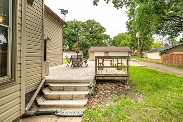 504 Laurel St, Fergus Falls, MN 56537 - wooden deck featuring outdoor dining space, a lawn, and an outbuilding