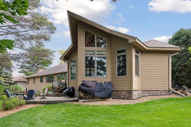 21273 Floral Bay Dr N, Forest Lake, MN 55025 - back of house with a patio, a lawn, stone siding, and a shingled roof