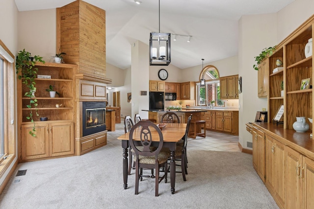 21273 Floral Bay Dr N, Forest Lake, MN 55025 - dining area with rail lighting, light carpet, a glass covered fireplace, and high vaulted ceiling